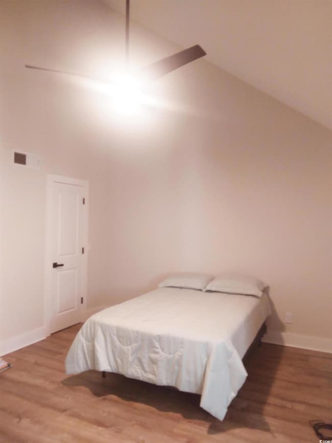 Bedroom with wood-type flooring and vaulted ceilin
