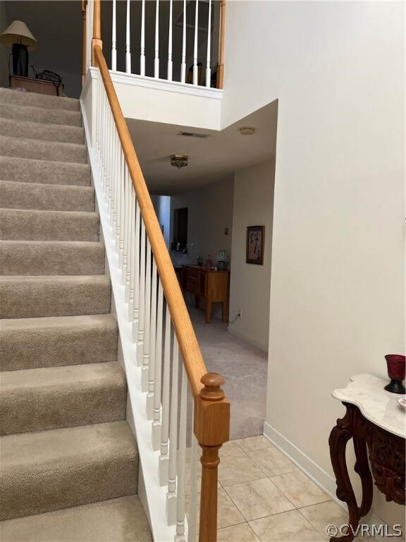 Stairs featuring light tile floors and a high ceil
