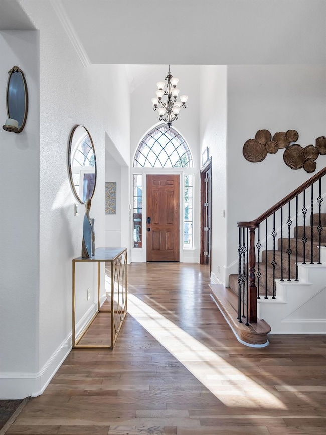 Foyer with crown molding, wood-type flooring, and a notable chandelier