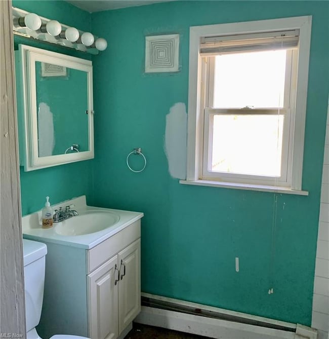 Bathroom with a baseboard radiator, mirror, and va