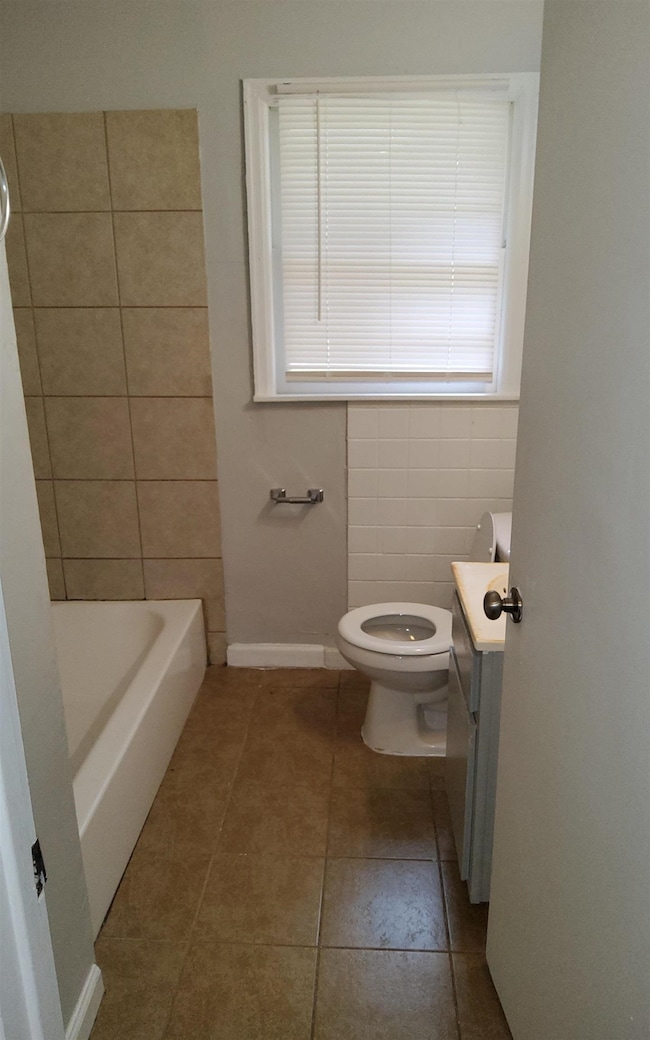 Bathroom with vanity, tile patterned floors, tile walls, and toilet