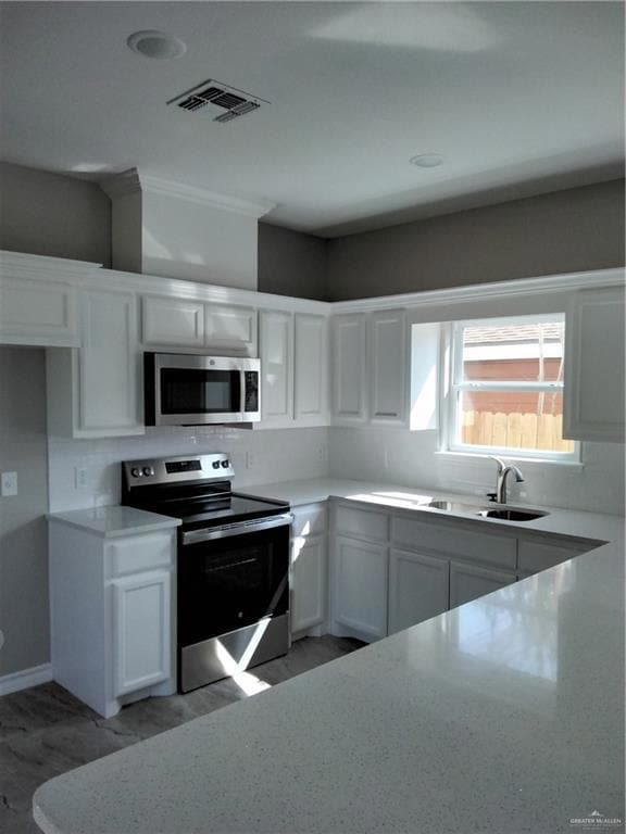 Kitchen with a sink, range, visible vents, white cabinets, and decorative backsplash