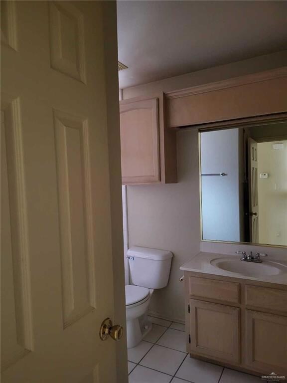 Bathroom featuring toilet, tile patterned flooring, and vanity