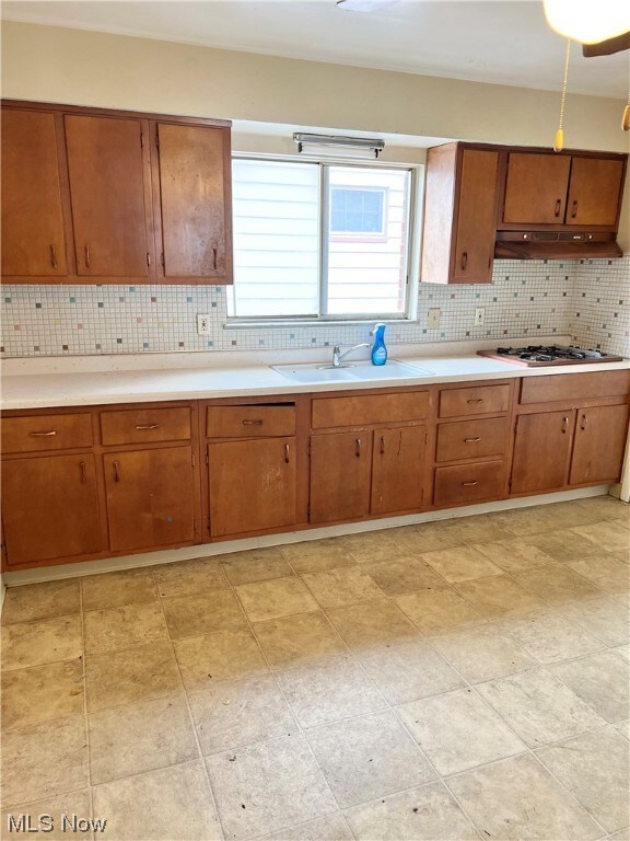 Kitchen with sink, gas cooktop, vinyl floor, and backsplash