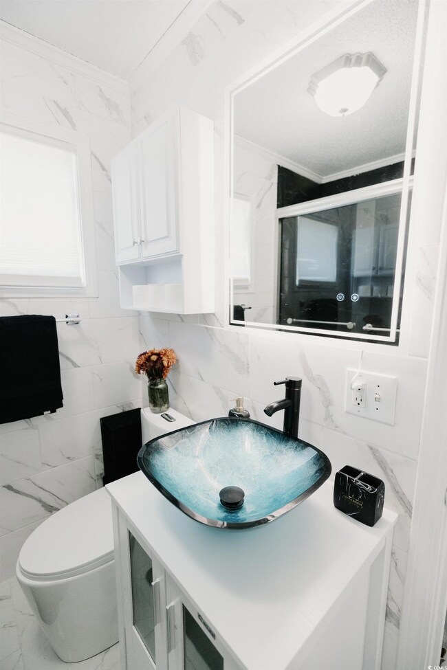 Full bathroom with tile walls, vanity, marble look tile flooring, and a shower stall