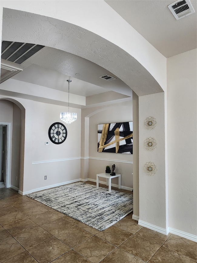 Dining space featuring arched walkways, tile patterned flooring, and a chandelier