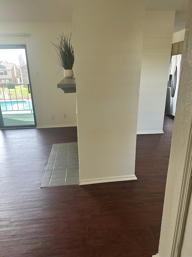 Empty room with dark wood-style floors and baseboa