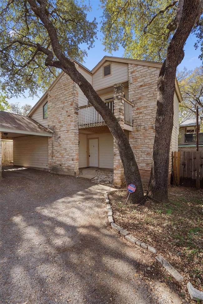 View of front of house with a balcony and stone siding
