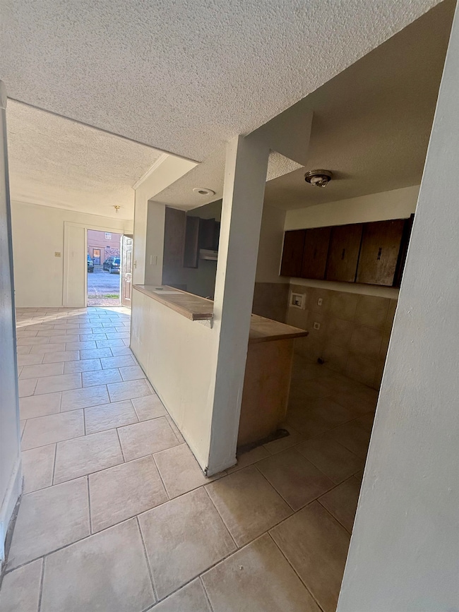 Hallway featuring a textured ceiling and light tile patterned floors