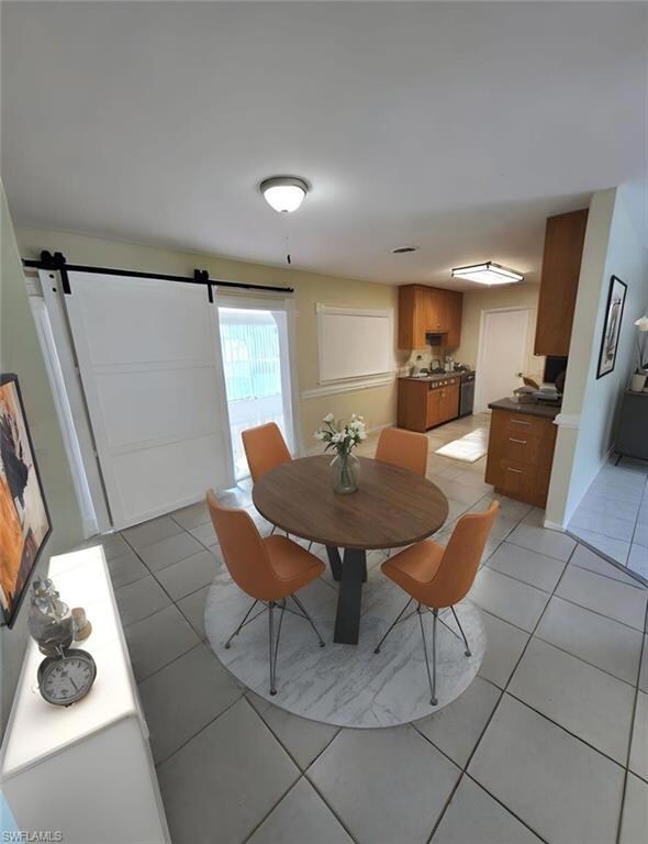 Dining area featuring a barn door and light tile patterned floors