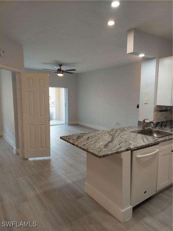 Kitchen featuring light wood-style flooring, recessed lighting, white cabinetry, light stone countertops, and dishwashing machine