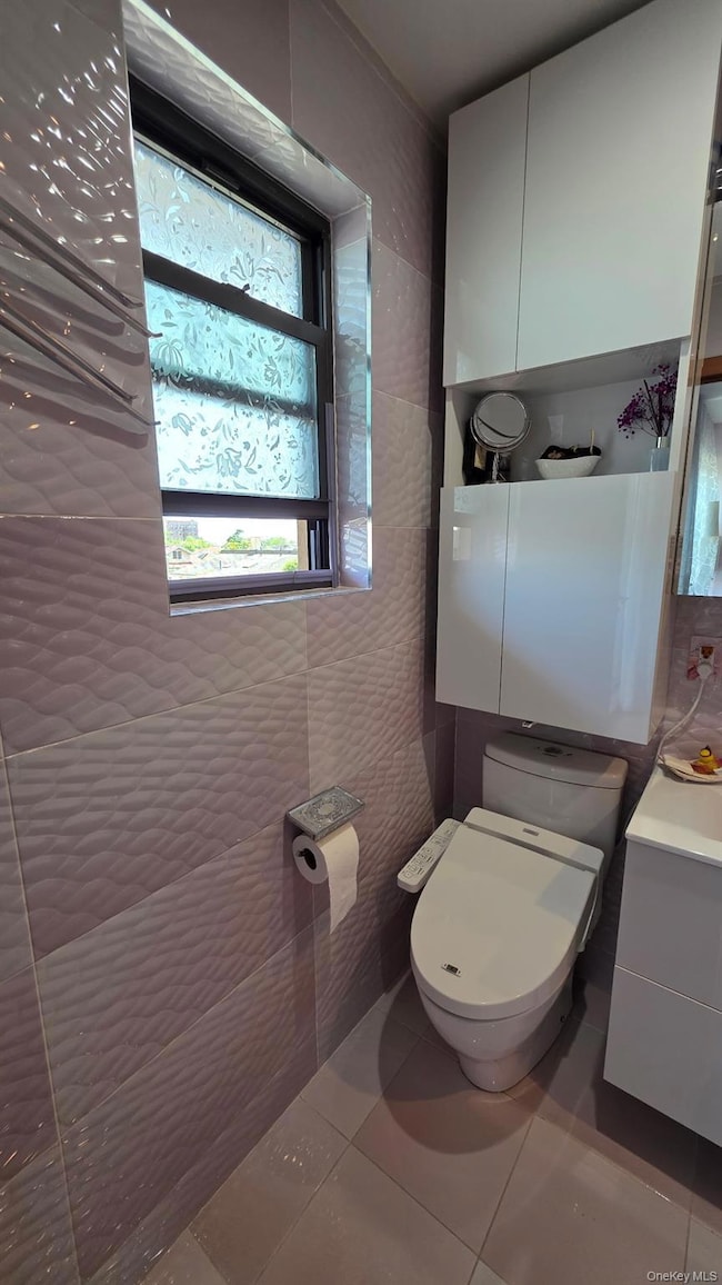 Bathroom with tile walls, tile patterned flooring, and vanity