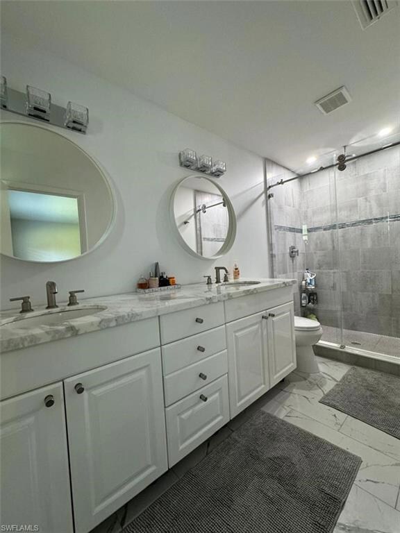 Luxury double-sink vanity with marble counters, round mirrors, and a frameless glass shower with sleek tile-work — designed for a spa-like feel.