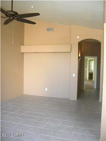 Living room with vaulted ceiling, pot shelf and newer ceiling fan.