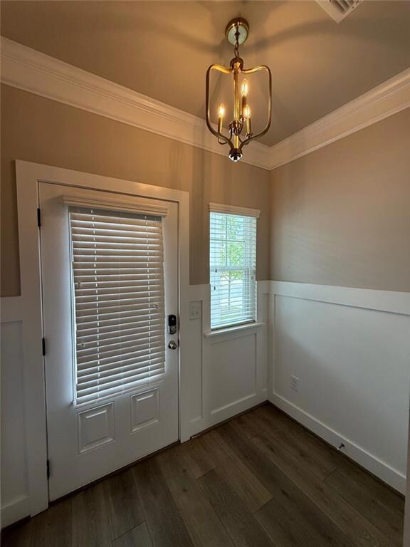 Entryway with crown molding, a wainscoted wall, da
