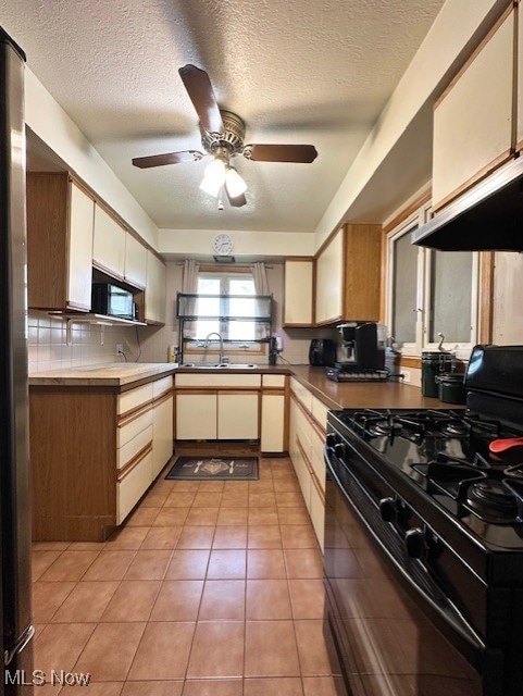 Kitchen with black appliances, light tile patterned floors, a textured ceiling, ceiling fan, and ventilation hood