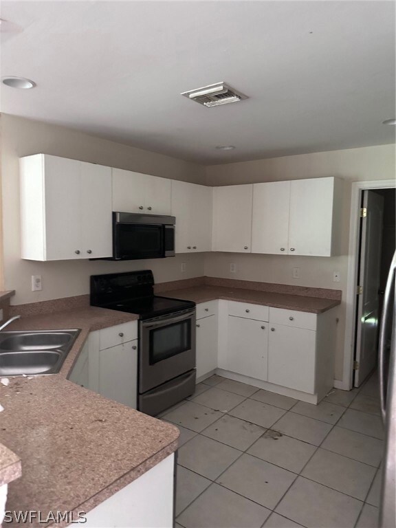Kitchen featuring white cabinets, stove, and light