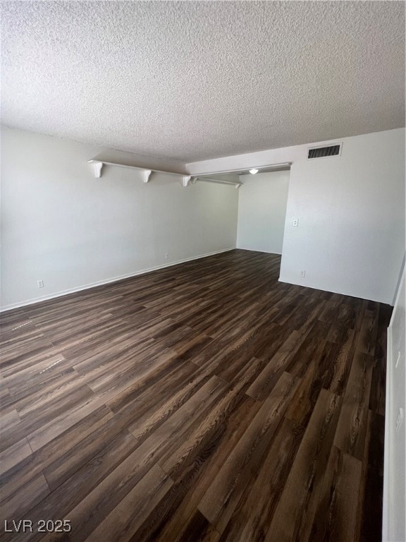 Empty room featuring dark wood-style flooring and a textured ceiling