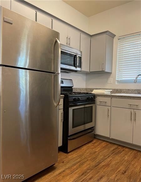 Kitchen featuring appliances with stainless steel finishes, light wood finished floors, and gray cabinetry