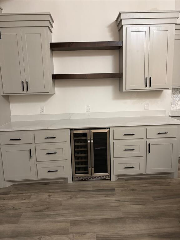 Bar with wine cooler and dark wood finished floors
