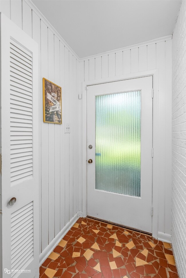 Doorway with wood walls and tile patterned floors