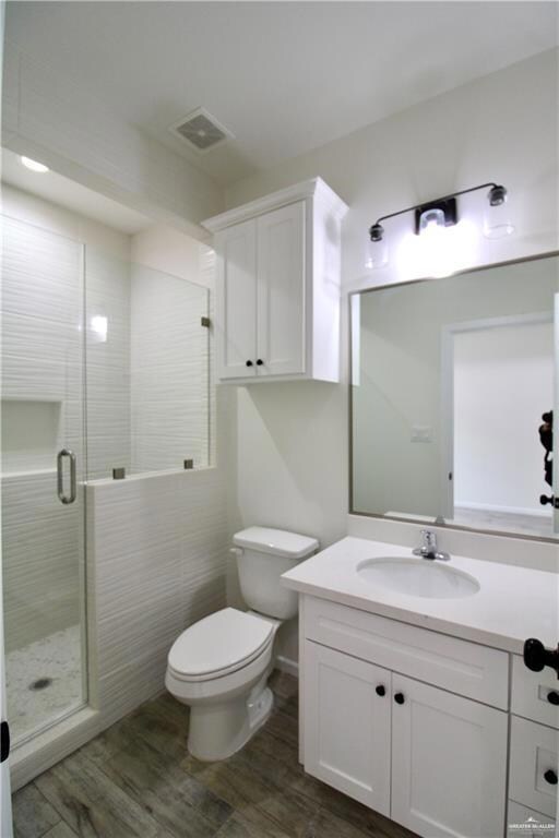 Full bathroom with vanity, dark wood-style flooring, and a stall shower