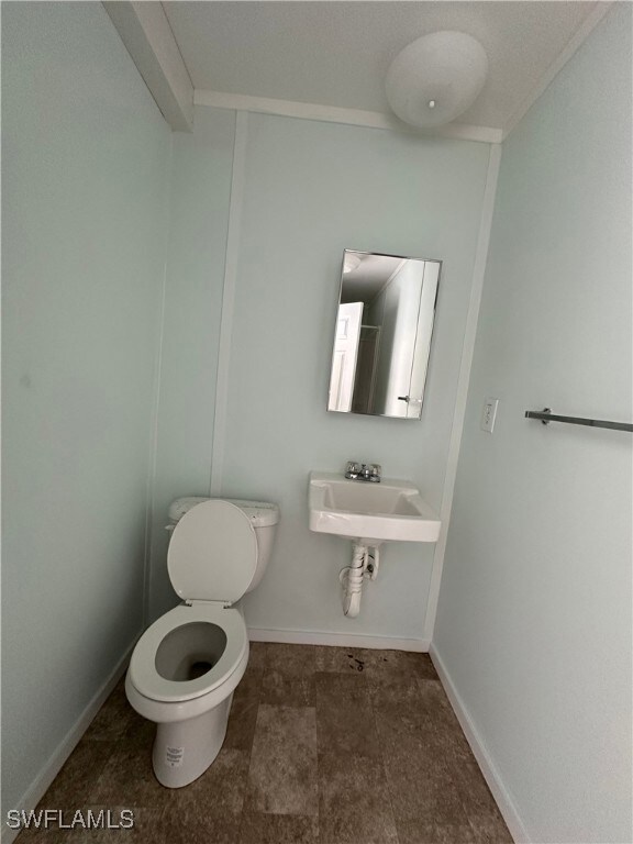 Bathroom with sink, ornamental molding, and toilet
