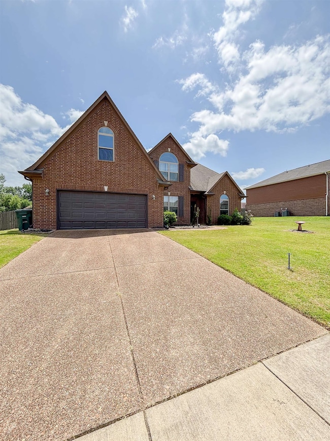 Traditional-style house featuring brick siding, a front lawn, and driveway
