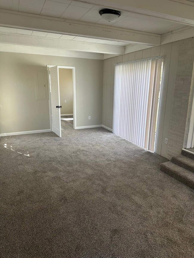 Carpeted spare room featuring beam ceiling and bas