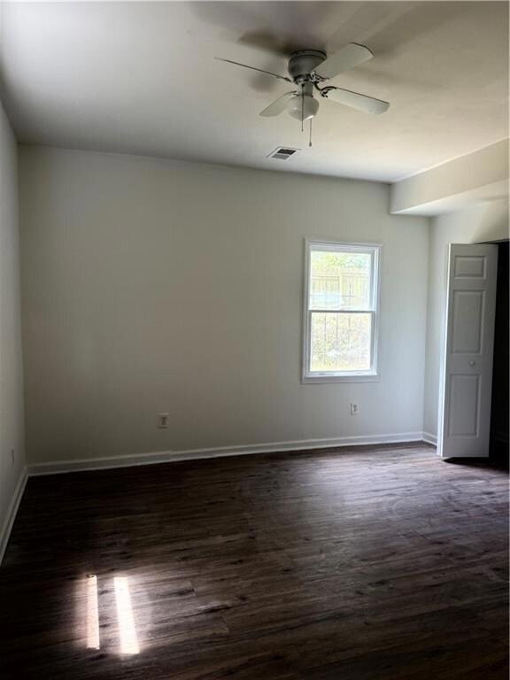 Unfurnished room featuring dark wood finished floors, ceiling fan, and baseboards