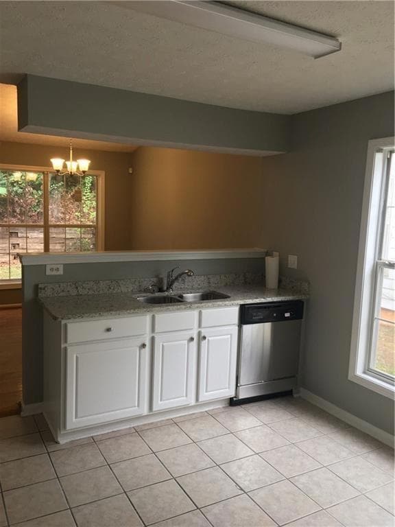 Kitchen with a sink, stainless steel dishwasher, a chandelier, white cabinetry, and light tile patterned flooring