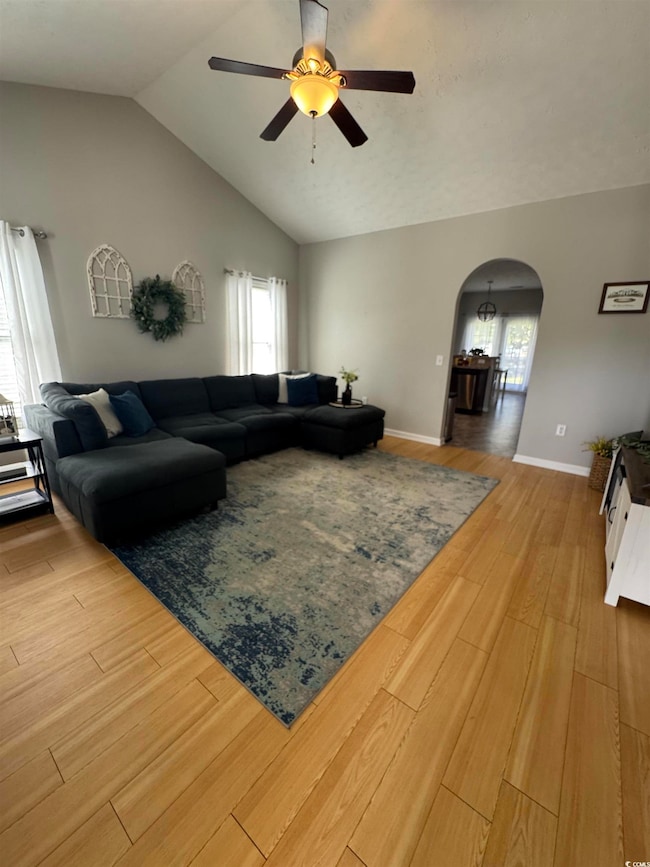 Living room with baseboards, arched walkways, ligh