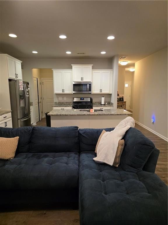 Living area featuring dark wood-type flooring and recessed lighting