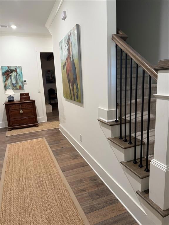 Hallway with baseboards, wood finished floors, stairway, crown molding, and recessed lighting