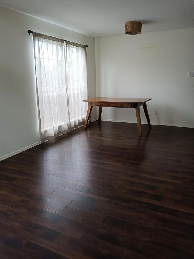 Empty room featuring baseboards and dark wood fini