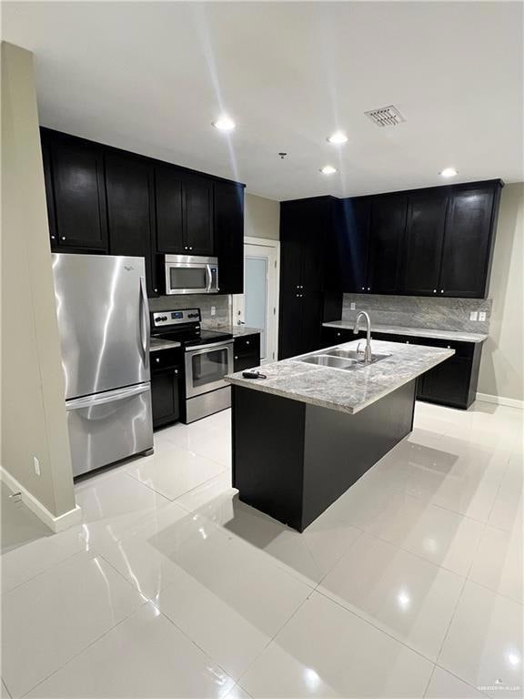 Kitchen featuring sink, light tile floors, backsplash, and appliances with stainless steel finishes