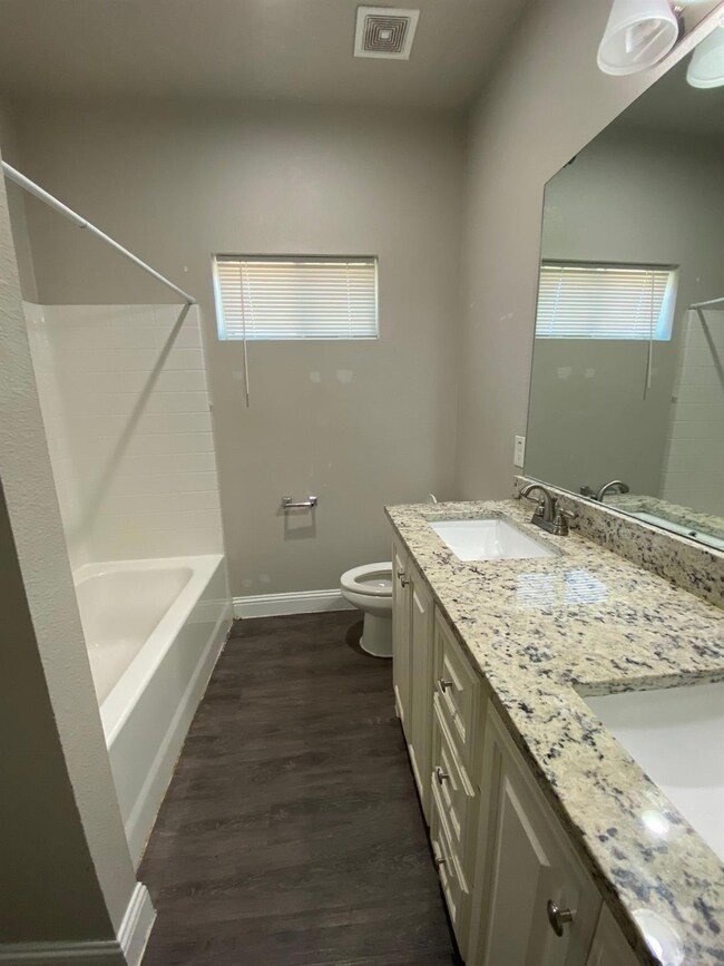 Full bathroom with baseboards, visible vents, toil