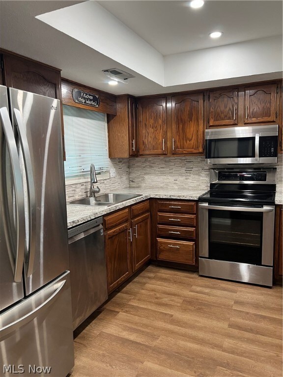 Kitchen featuring range, tasteful backsplash, light hardwood / wood-style floors, refrigerator, and dishwasher
