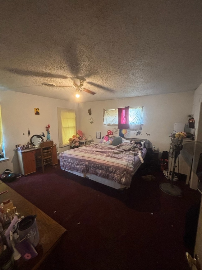 Carpeted bedroom featuring a textured ceiling and a ceiling fan
