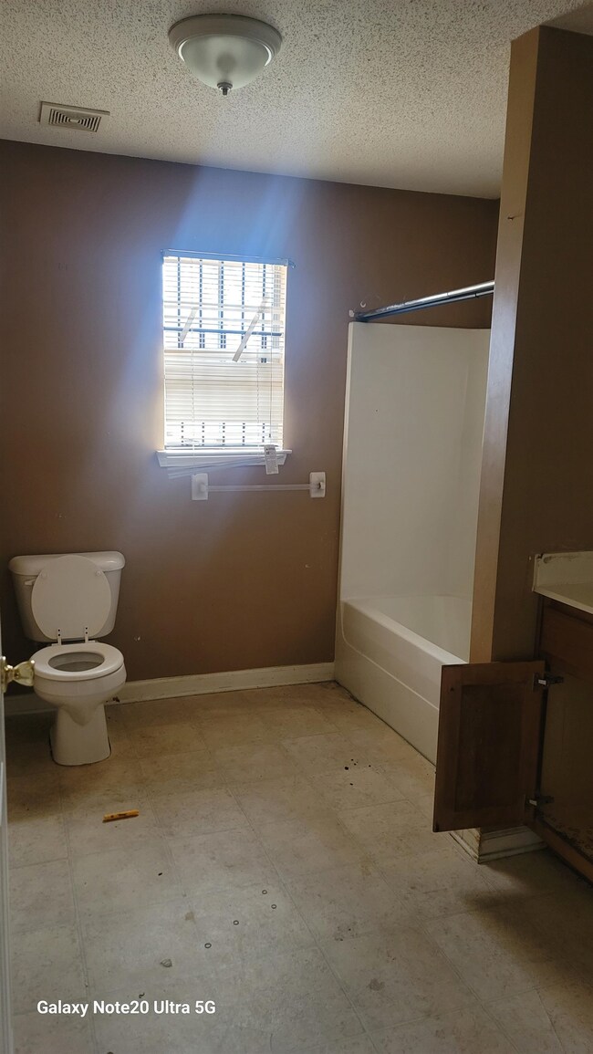Bathroom with a textured ceiling, toilet, and vani