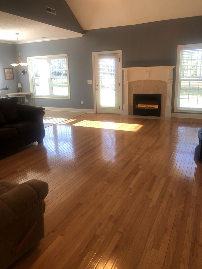 Spacious living room with beautiful hardwood floors, gas fire insert and large windows to view of the backyard