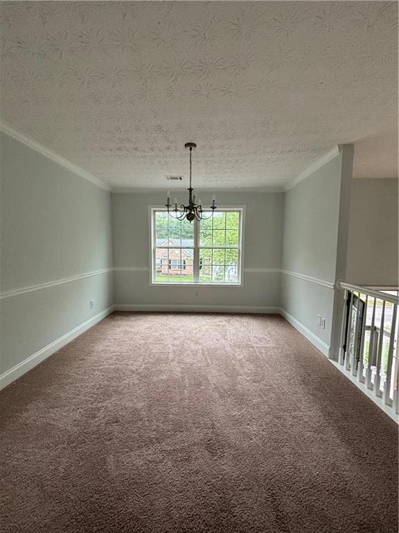 Spare room featuring ornamental molding, a chandelier, a textured ceiling, carpet floors, and baseboards
