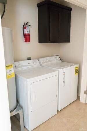 Washroom featuring separate washer and dryer, cabinet space, and water heater