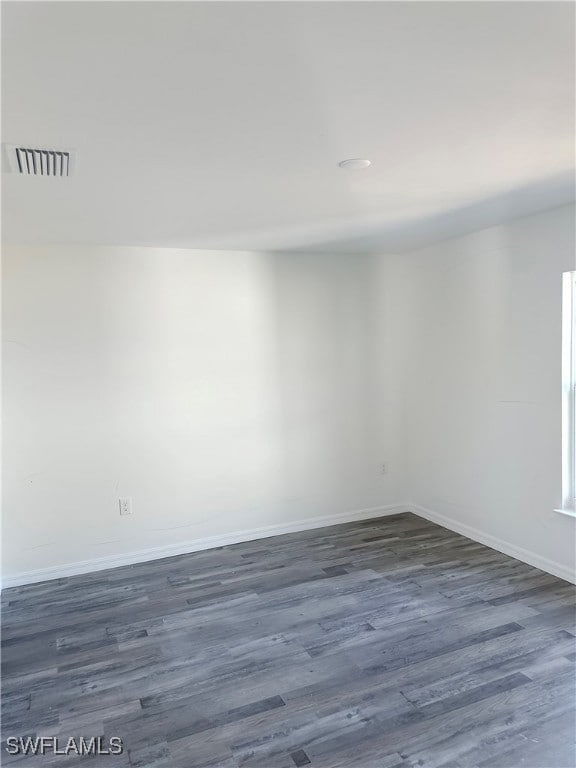 Empty room with dark wood-style flooring and baseb