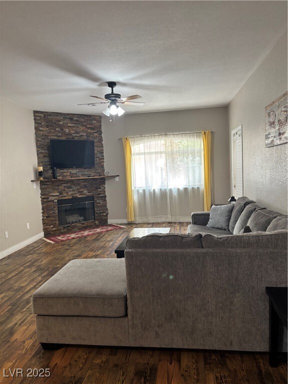 Living room featuring ceiling fan, a stone firepla
