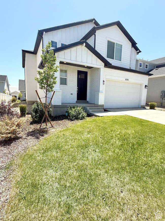 Modern farmhouse style home featuring an attached garage, a front yard, concrete driveway, board and batten siding, and brick siding