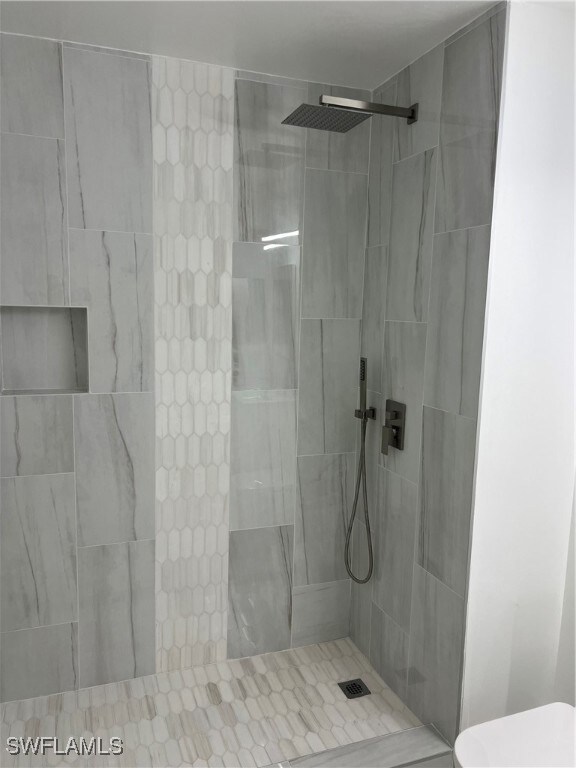 Bathroom featuring tiled shower and toilet