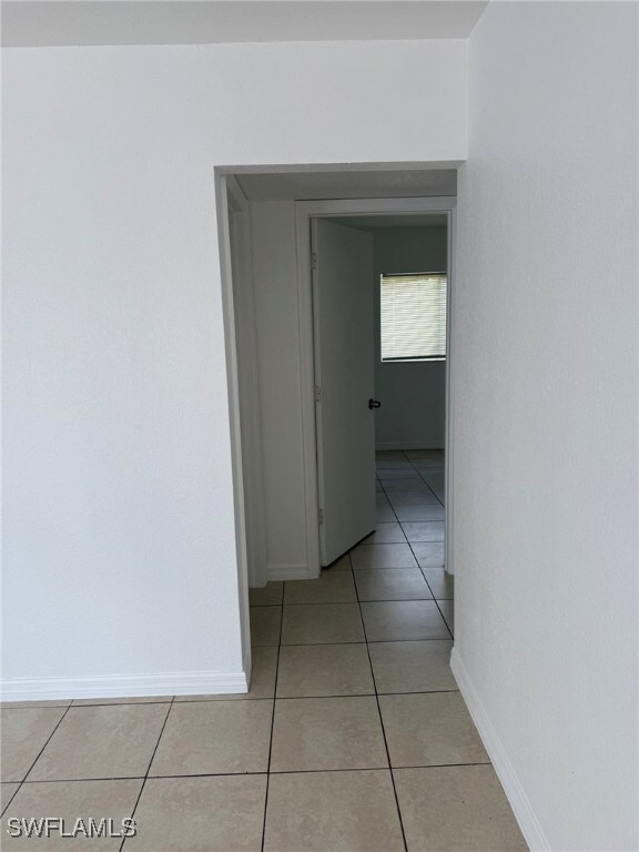 Corridor with light tile patterned flooring and ba