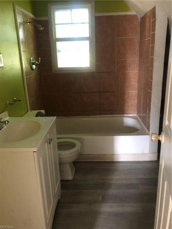 Full bathroom featuring dark hardwood flooring, vanity, and tiled shower / bath