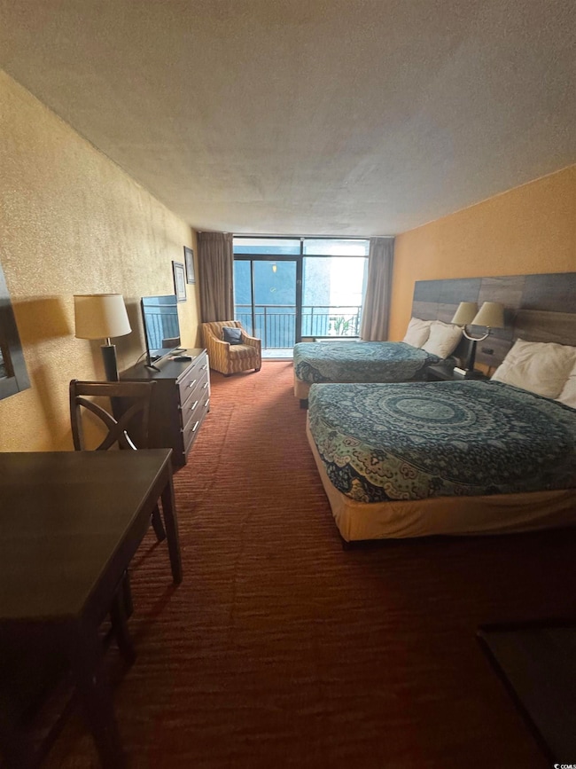 Bedroom with a textured wall, carpet floors, access to outside, a wall of windows, and a textured ceiling